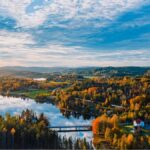 Höstvy över samhälle, flygbild, vatten och skog i olika färger.