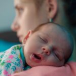 Nyfödd bebis sover på vuxens axel.