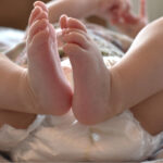 Spädbarn i blöja ligger på en säng.