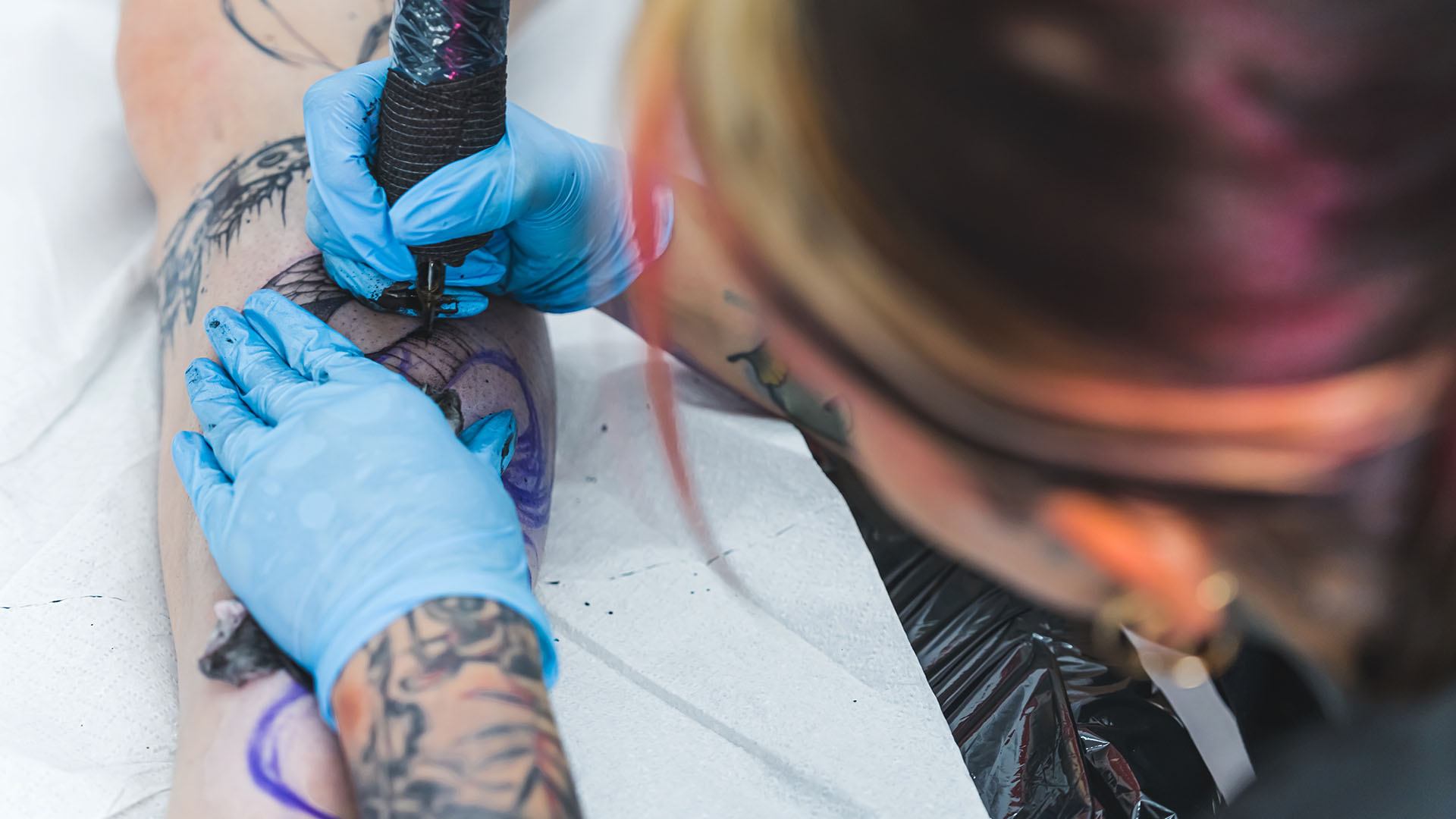 Tatuerare arbetar med en tatuering på ett ben.