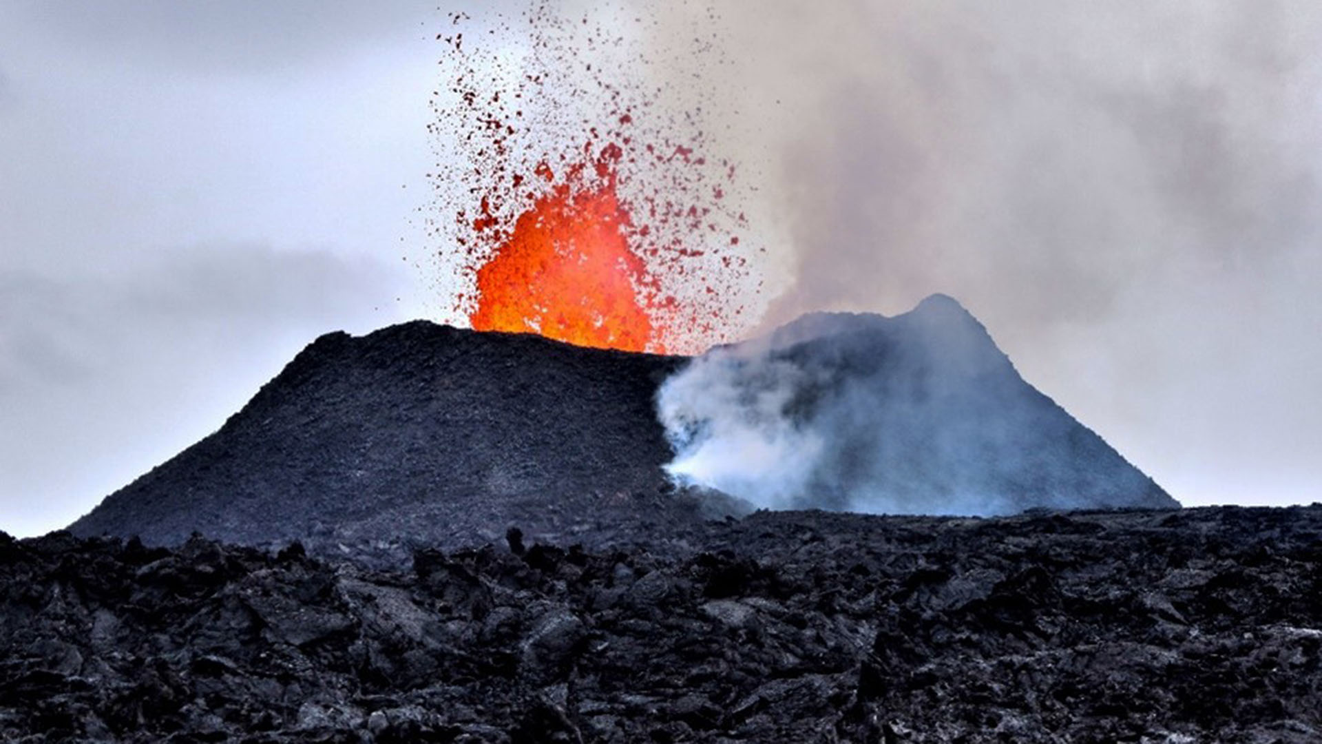 Lava sprutar upp från vulkanens inre och bildar tjock rök och aska.