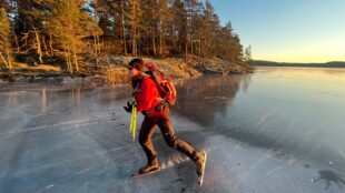 Skridskoåkare i röd jacka på en sjö.