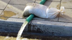 Vatten pumpas ut på trottoar.