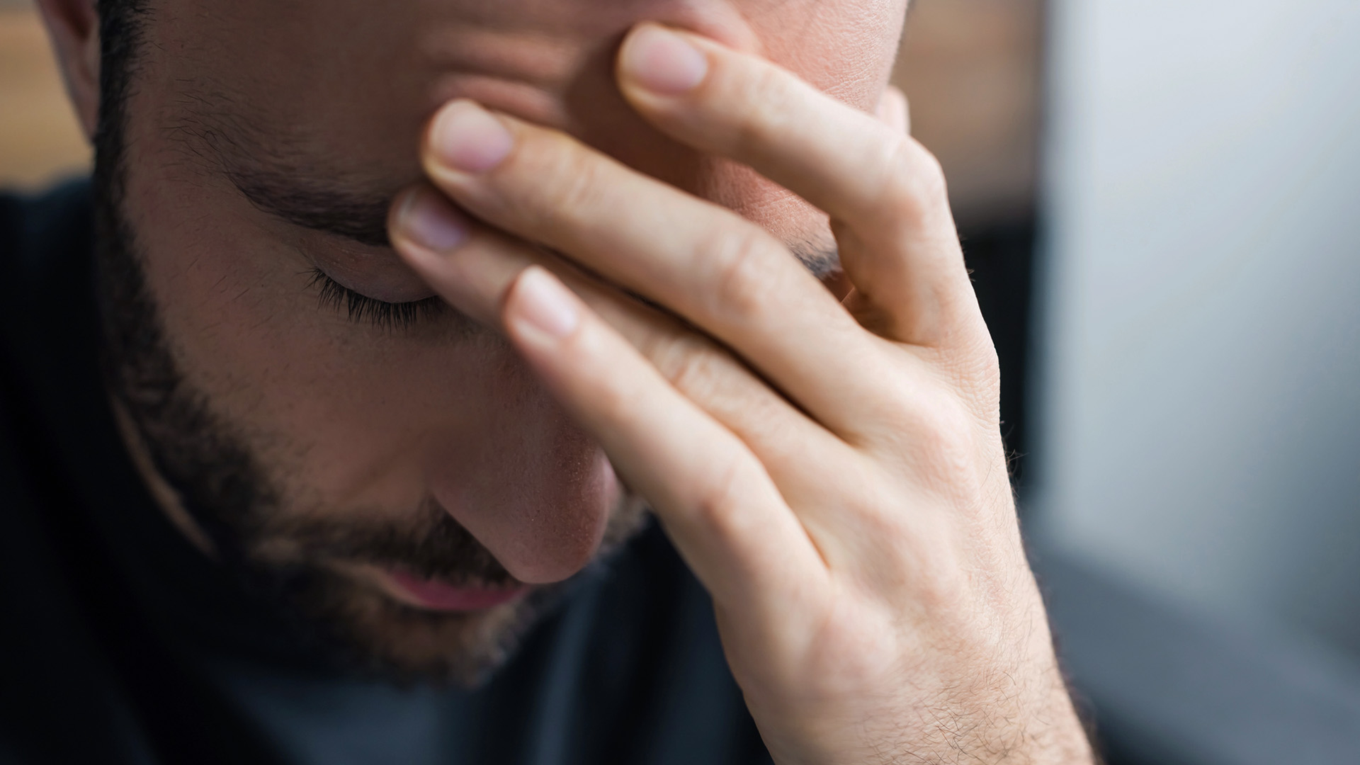 En man som ser trött ut håller upp ena handen mot pannan.