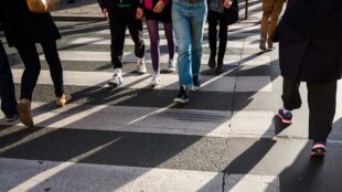 Människor går åt olika håll vid övergångsställe.