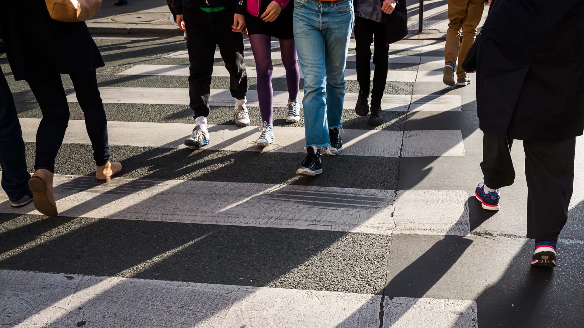 Människor går åt olika håll vid övergångsställe.