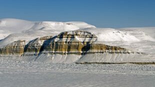 Snö och is breder ut sig över bergliknande formation.