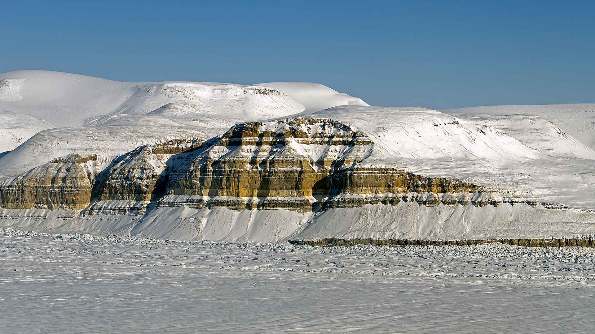Snö och is breder ut sig över bergliknande formation.