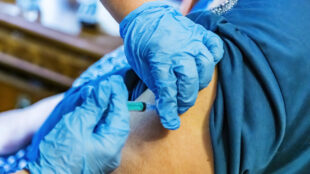 Sjukvårdspersonal vaccinerar en äldre kvinna.