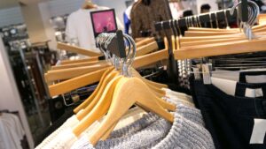 Butik med tröjor och byxor på galgar.