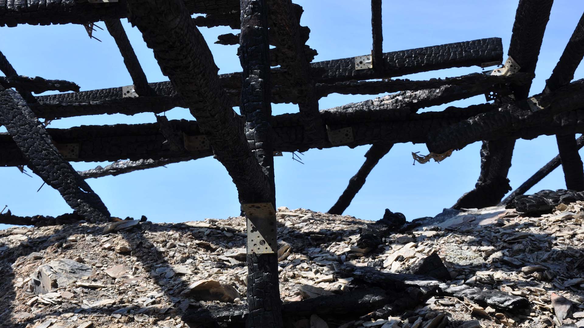 Utbränd byggnad med förkolnade bjälkar.