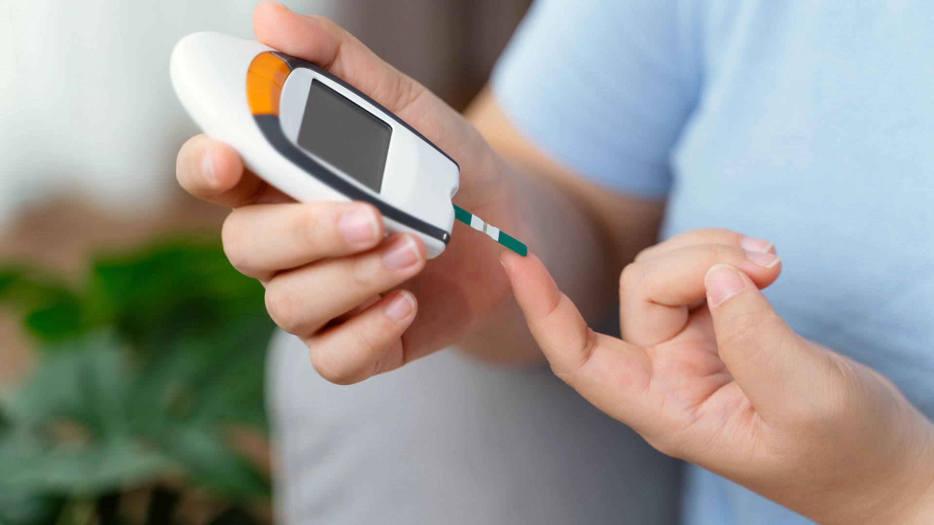 Person testar sitt blodsocker med en glukosmätare.