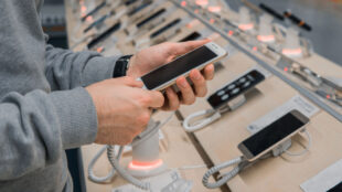 Man inspekterar olika mobiler i affär.