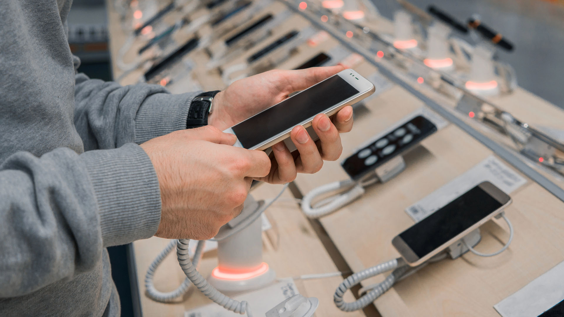 Man inspekterar olika mobiler i affär.