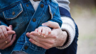 Pappa håller om ett barns händer.