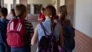 Barn med ryggsäckar i en skolkorridor.