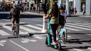 Elsparkcykel och andra cyklar på gata i storstad.