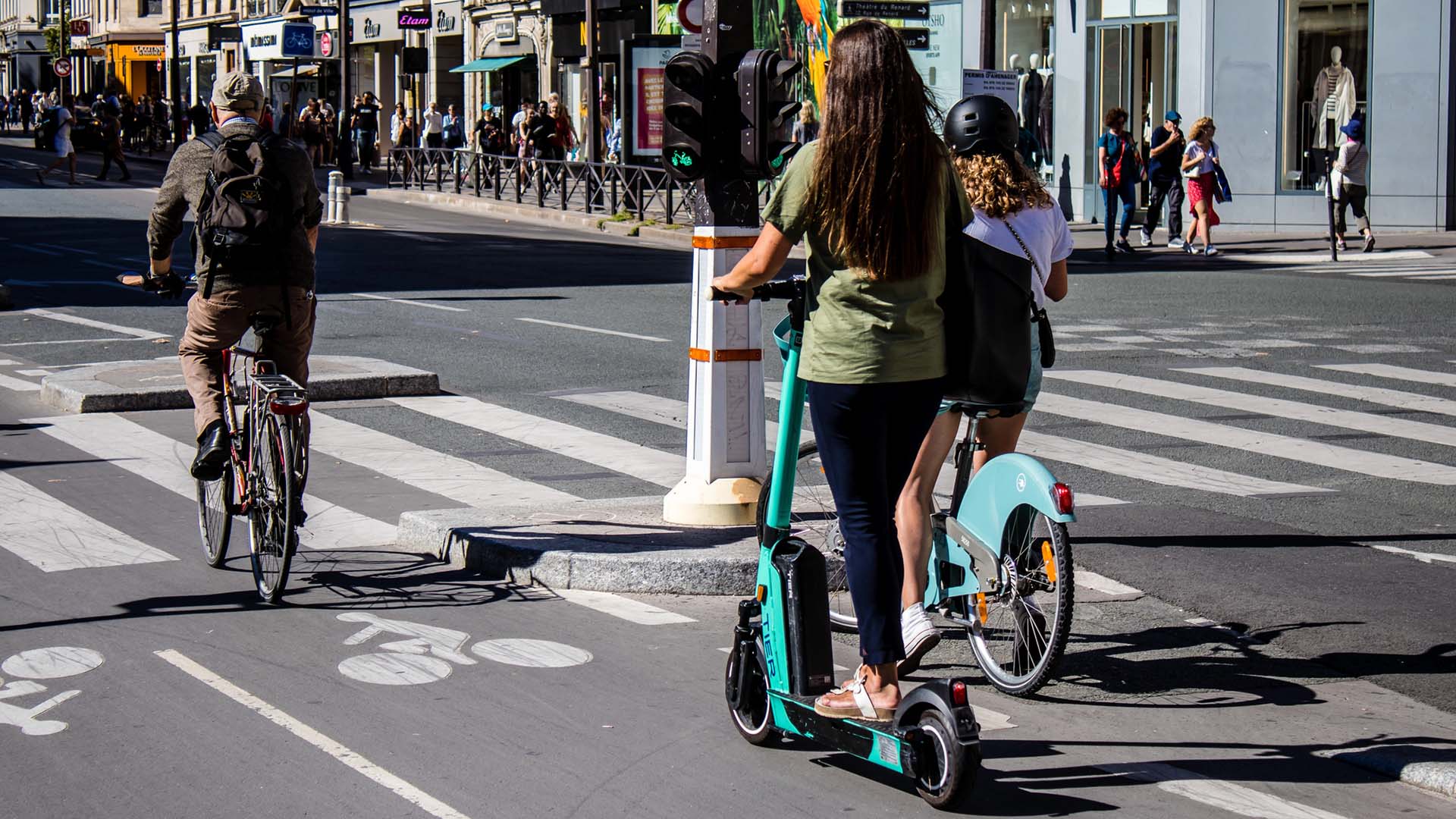 Elsparkcykel och andra cyklar på gata i storstad.