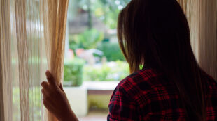 Kvinna tittar ut genom ett fösnter.