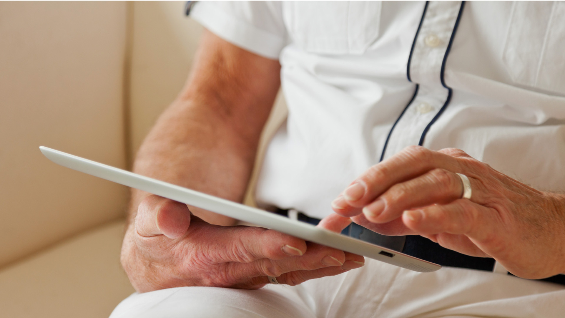 Man siter med en läsplatta i en soffa.