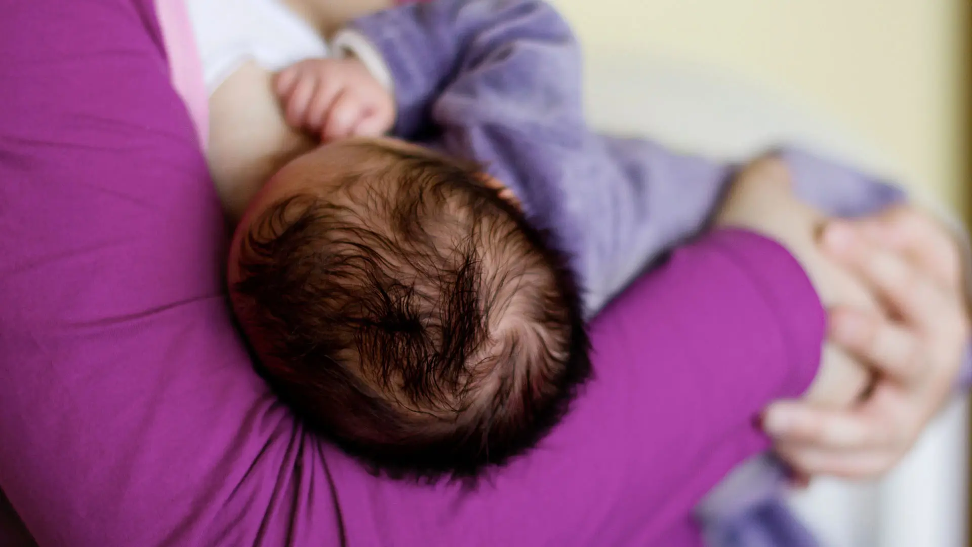 Bebis med mörkt hår ammas.