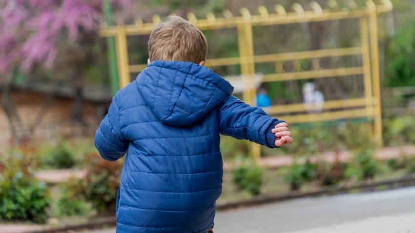 Pojke med blå jacka springer i park