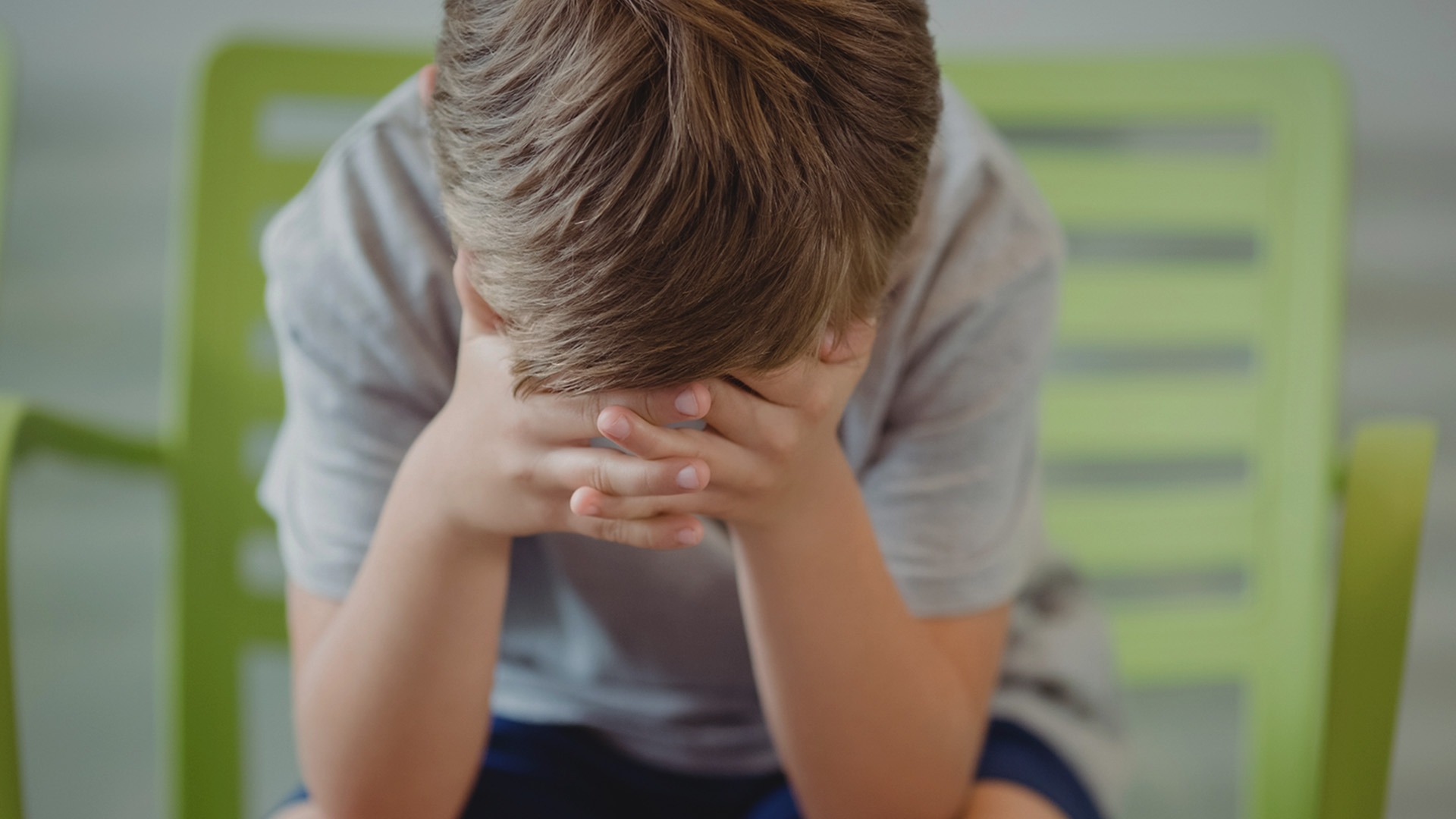 Pojke döljer sitt ansikte.