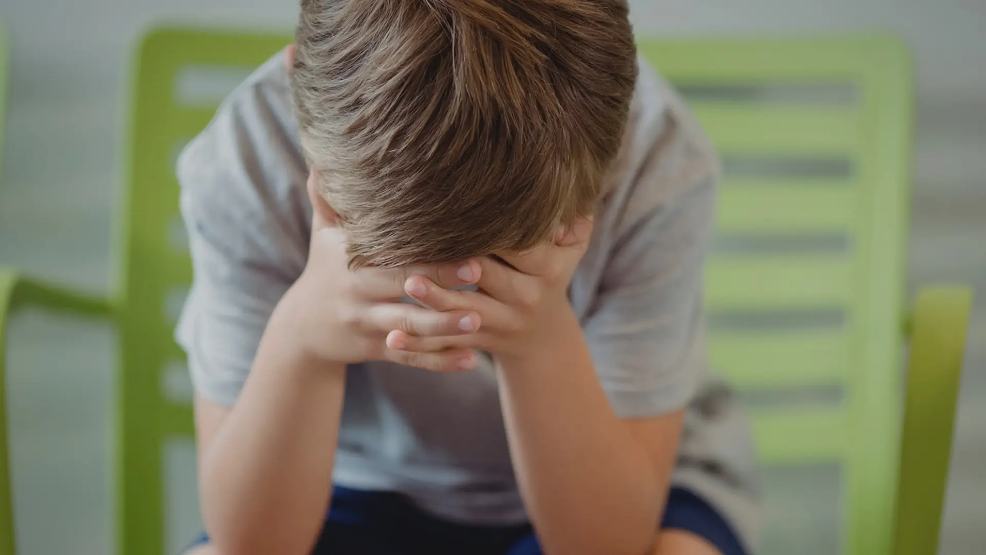 Pojke döljer sitt ansikte.