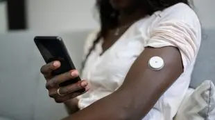 Person med knapp på armen för kontroll av blodsocker.