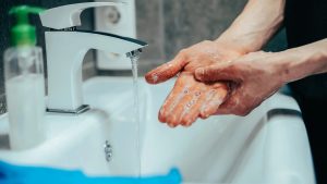 Man tvålar in sina händer i ett badrum.