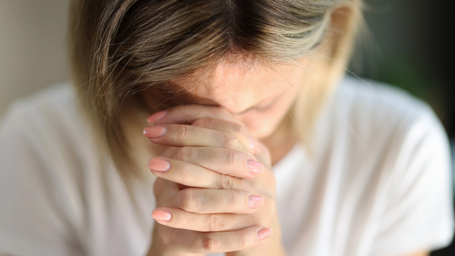 Kvinna med rosa nagellack håller händerna framför ansiktet.