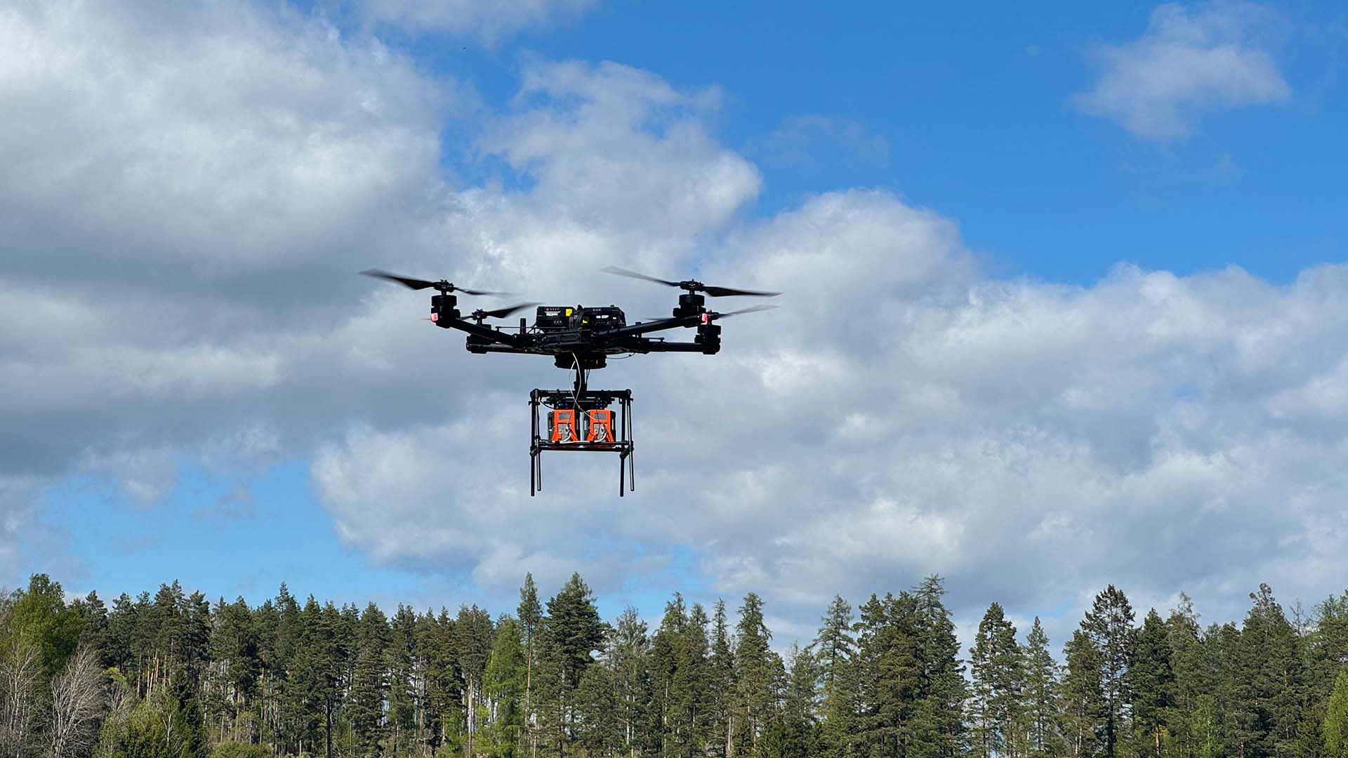 Drönare flyger över skogsområde.