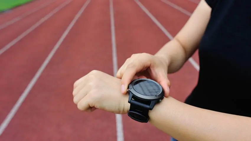 Friidrottare kollar en träningsklocka.