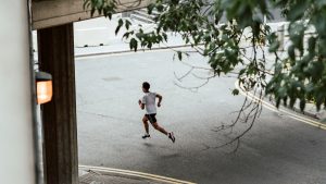 Ung man träningsspringer på gata.