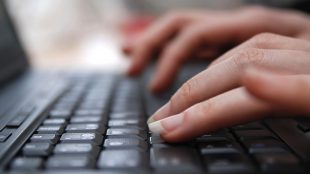 Två händer på ett tangentbord, närbild.
