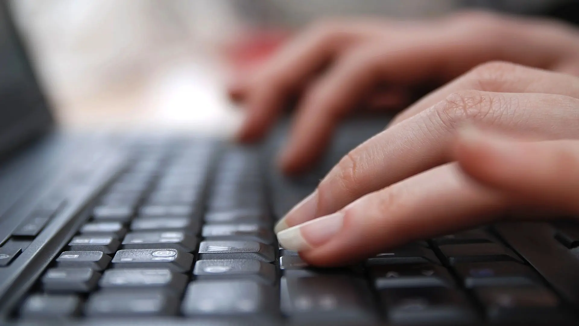 Två händer på ett tangentbord, närbild.