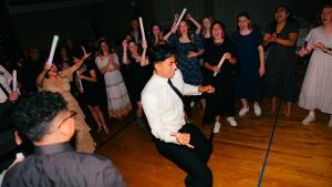 Människor dansar på fest. En ung man i vit skjorta i mitten.