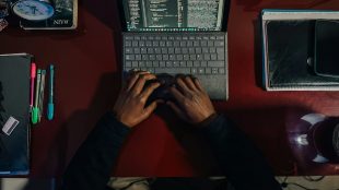 Två händer på en laptop, sett uppifrån.