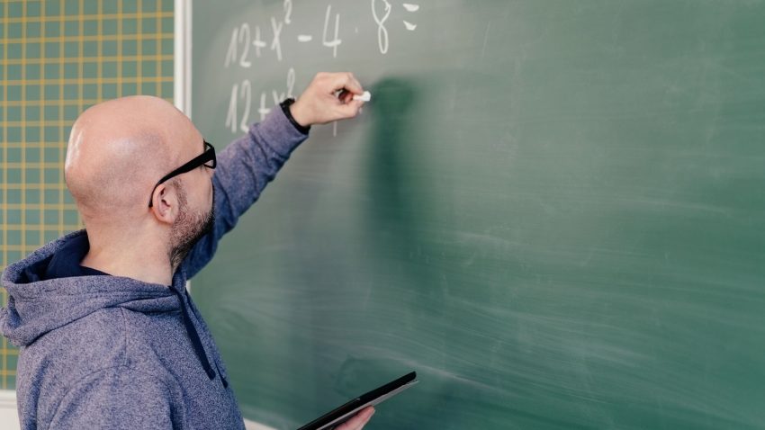 Lärare skriver tal på tavla.