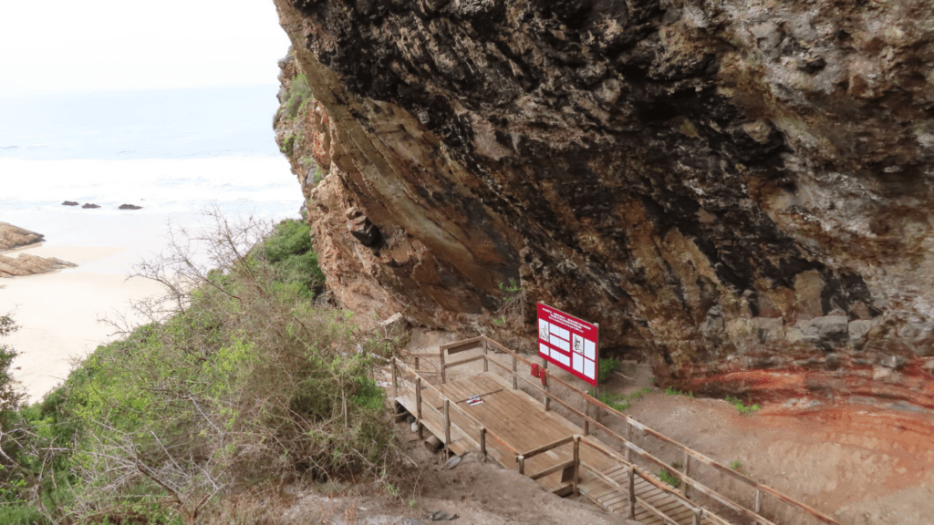 En klippa med stig nedanför, hav i bakgrunden.