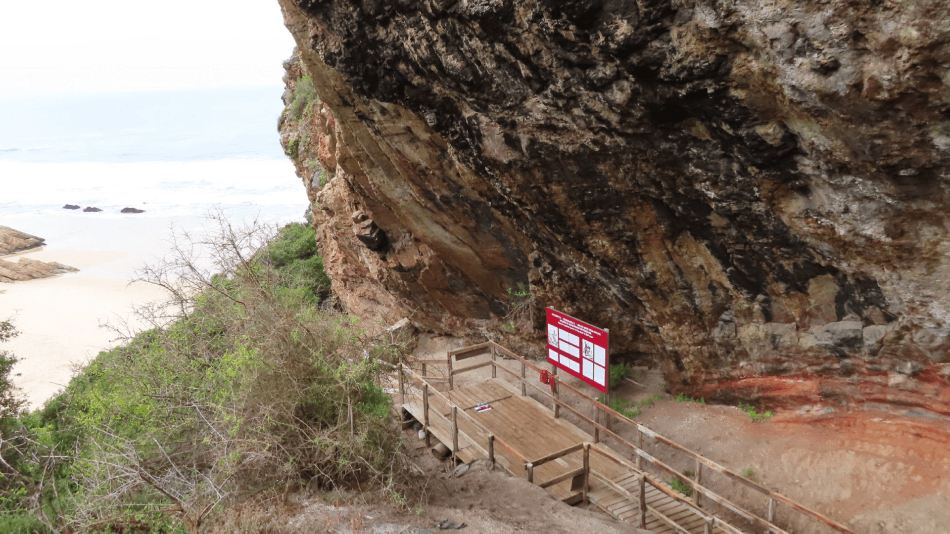 En klippa med stig nedanför, hav i bakgrunden.