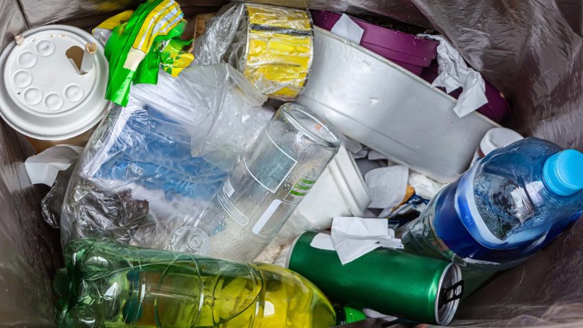 Plastflaskor, matkartonger och lock i en soptunna.