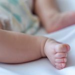 Bebisfötter i säng.