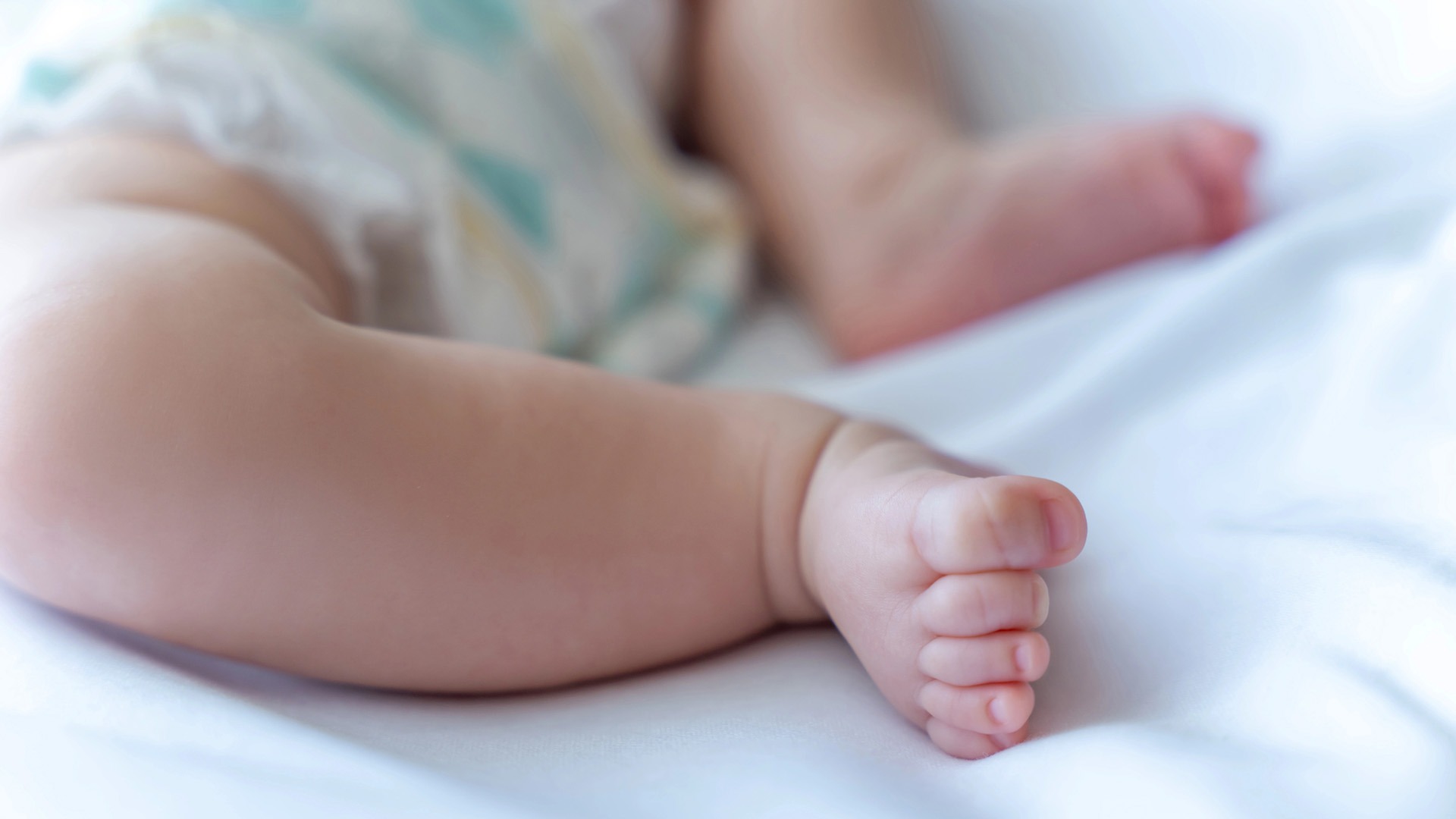 Bebisfötter i säng.