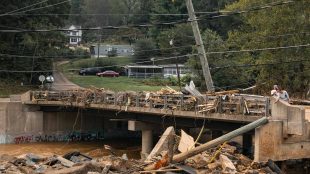 Skadad bro över flod och svajiga elledningar.
