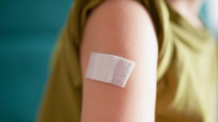 Plåster på överarm efter vaccination.