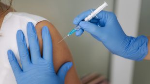 Kvinna vaccineras med spruta i armen.