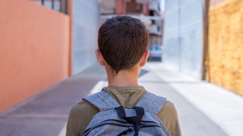Pojke med ryggsäck på väg mot skola.