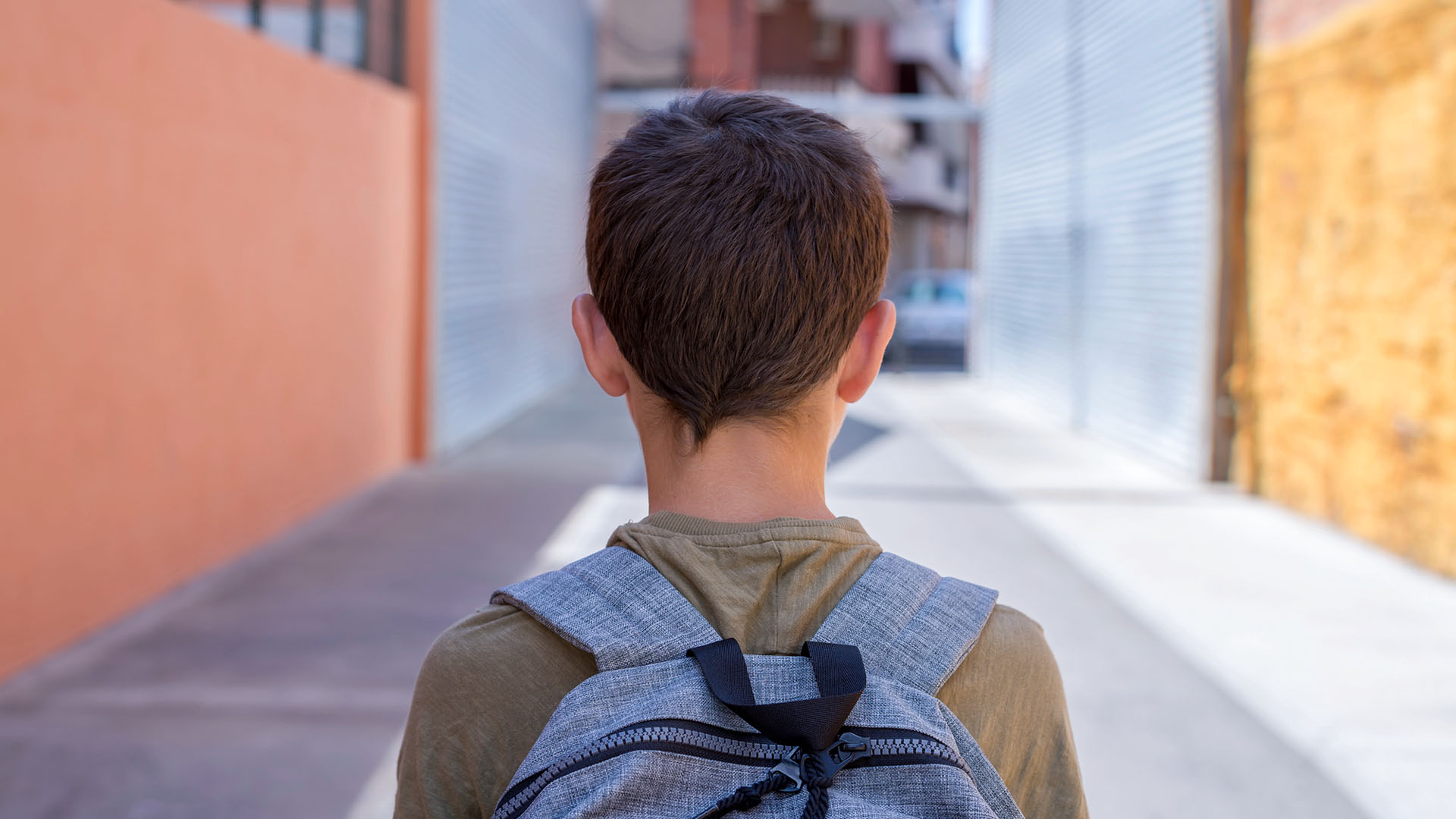 Pojke med ryggsäck på väg mot skola.