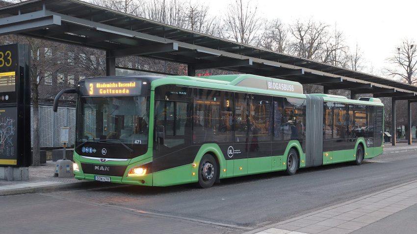En grön buss står stilla på busstation.
